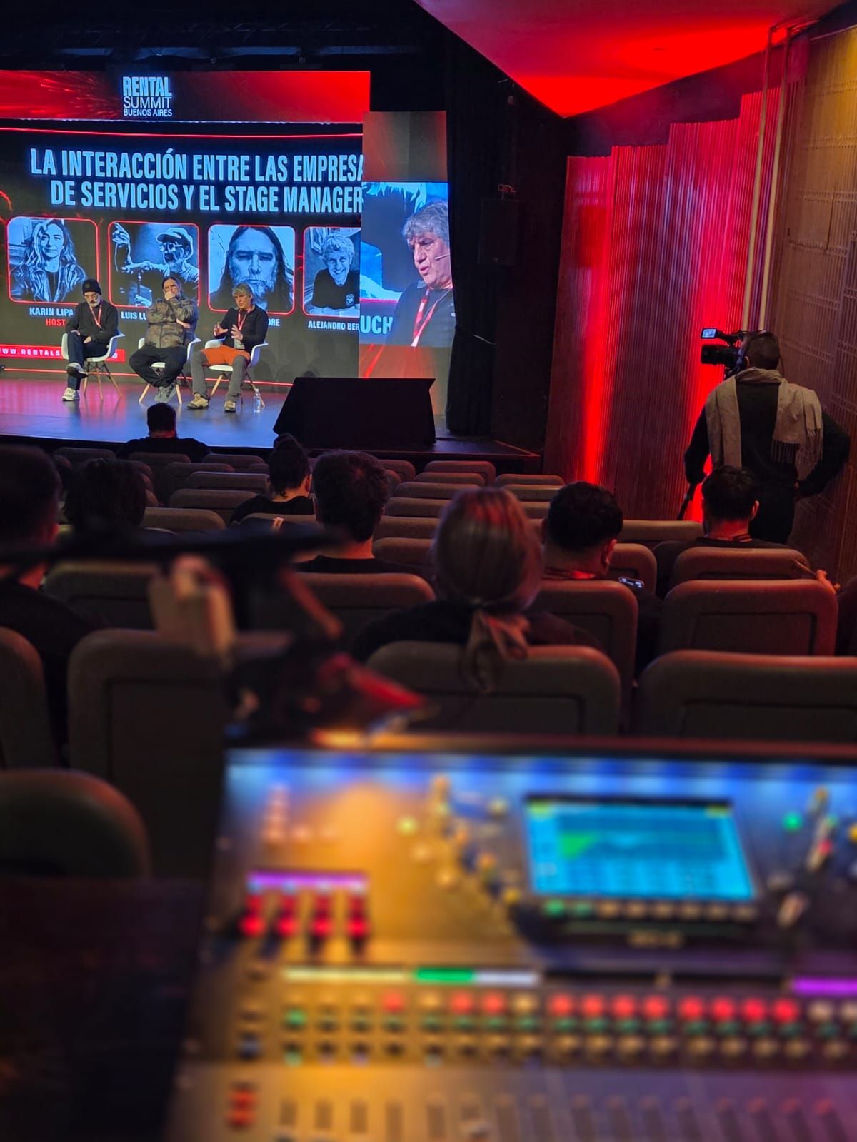 Consola de audio operando en sala con el público siguiendo la charla