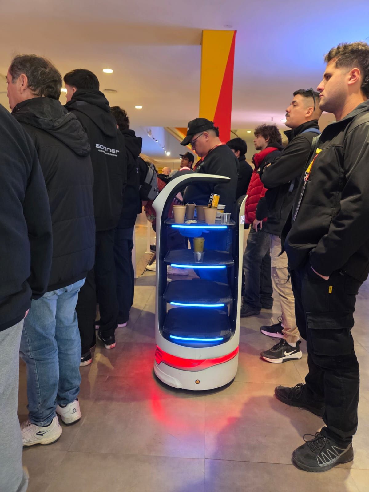 Robot de servicio con branding del Rental Summit circulando entre los asistentes en el hall