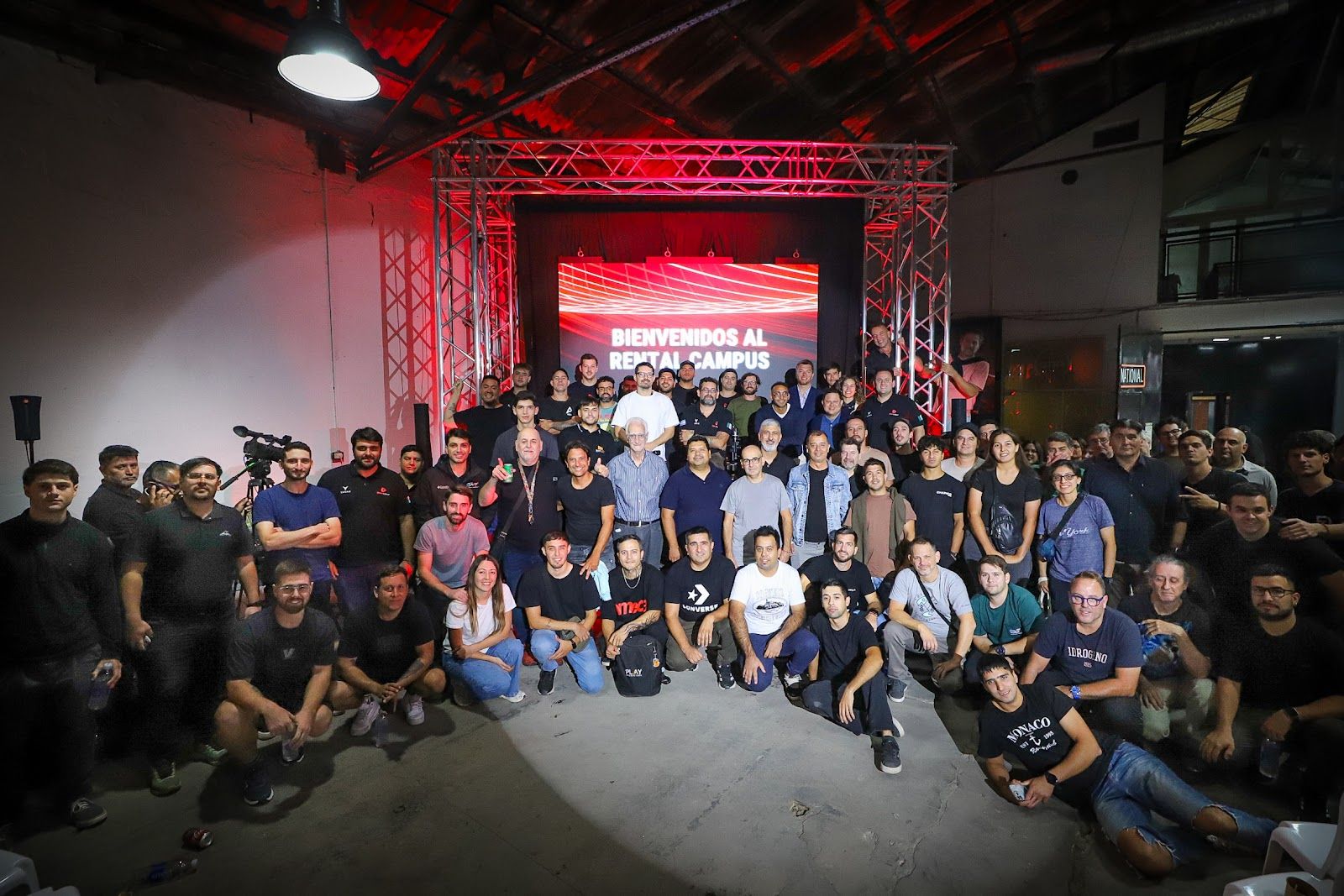 Foto grupal de los asistentes al Rental Campus frente a la pantalla de bienvenida